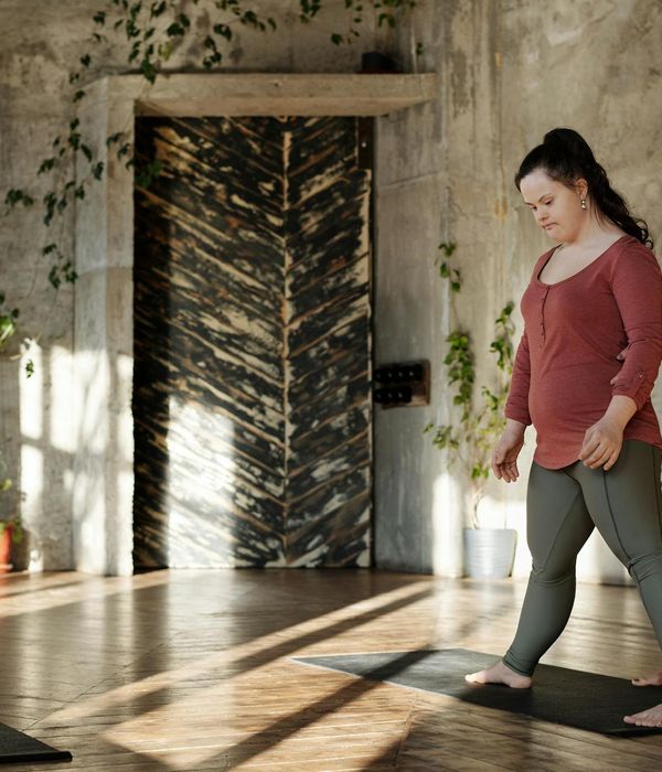 Person practicing gentle yoga movements in a dark blue room
